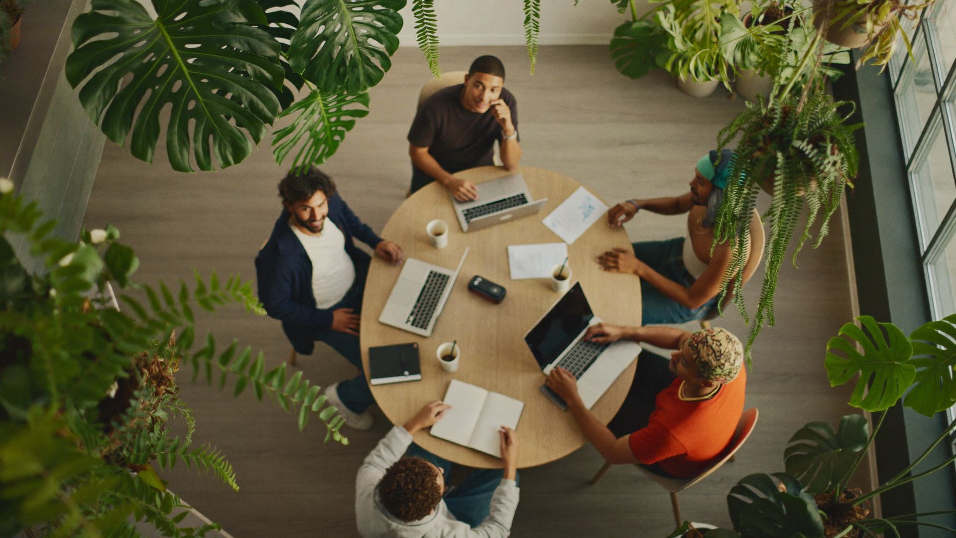 Réunion de travail vue de haut entre une équipe informatique et son client, dans un open space végétalisé